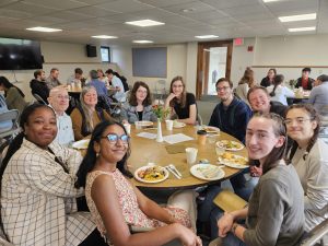 College students enjoy lunch around the table with church staff